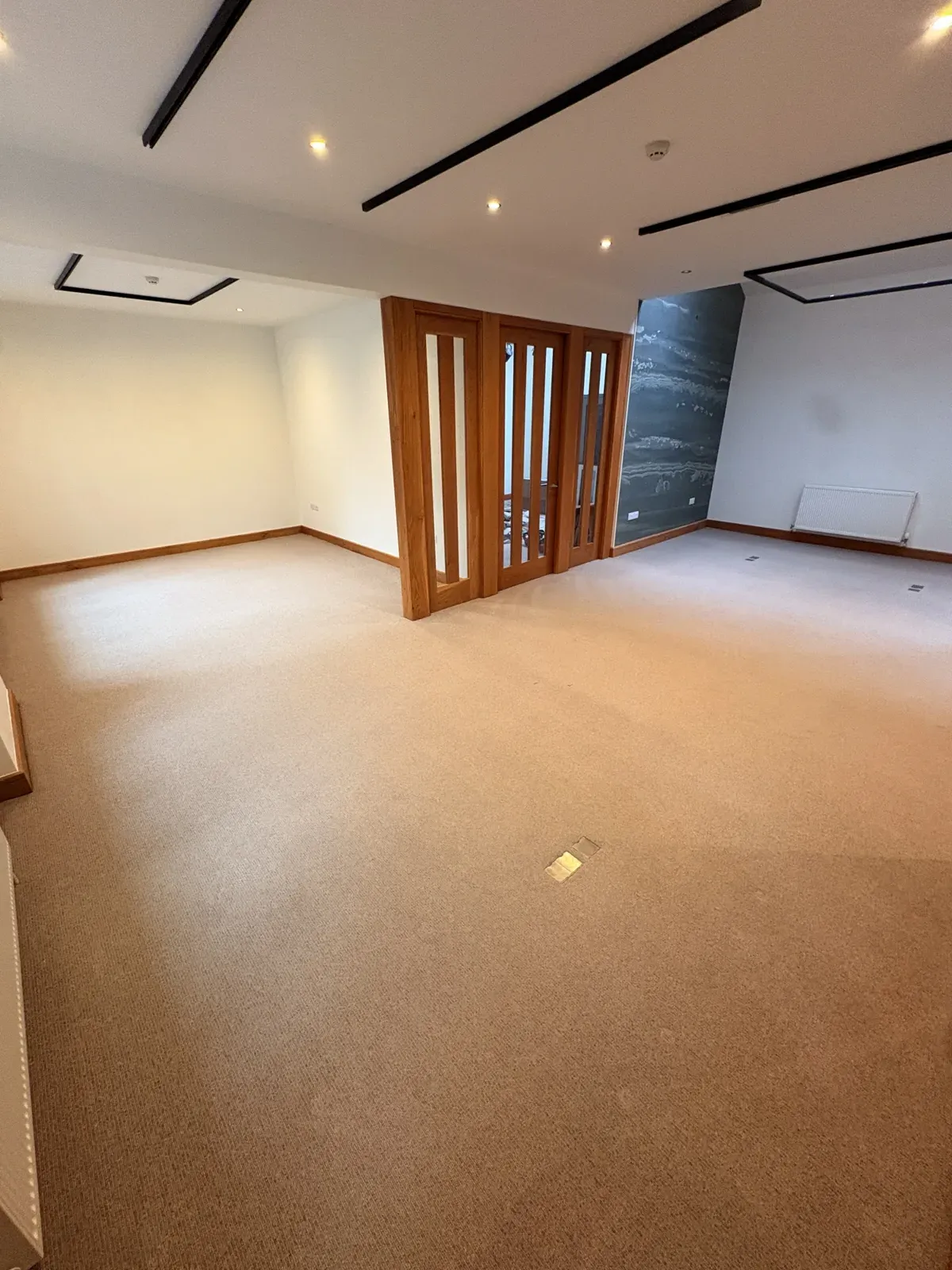 Upstairs studio at KORE Wellbeing — carpeted open-plan room with oak-framed doors